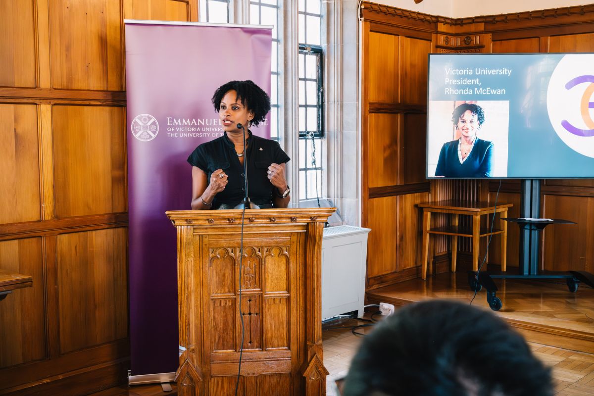 Victoria University President, Rhonda McEwen, stands at a podium to speak to the new incoming class of students at Emmanuel College.