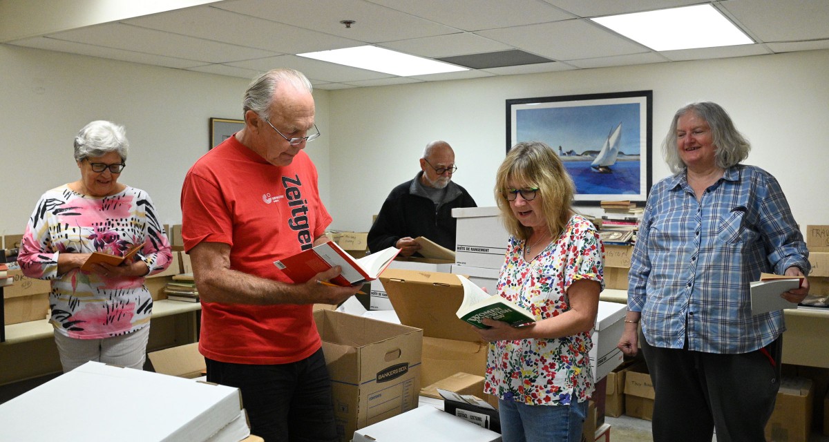 Book sale volunteers pose for a photo in a donation sorting room.