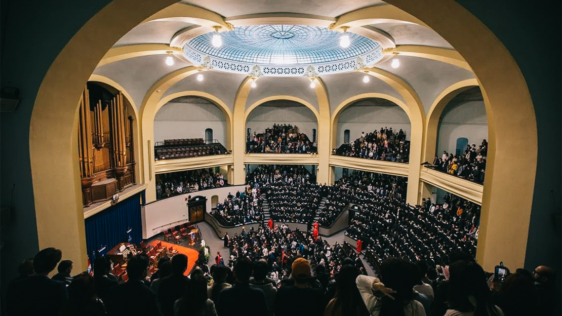 Graduates fill convocation hall as they wait seated, about the cross the stage