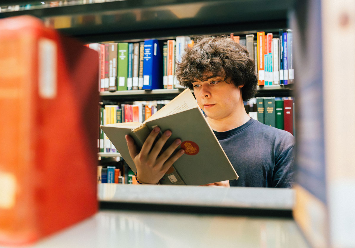 Vic student Shane Joy reading a book in the EJ Pratt library.